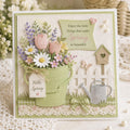 Spring card with green flower bucket, birdhouse, watering can, fence, and hello spring tag
