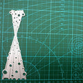 Silver metal cutting die with bubble spray pattern shown on green gridded cutting mat