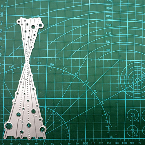 Silver metal cutting die with bubble spray pattern shown on green gridded cutting mat
