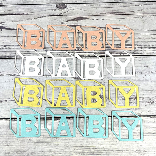 Four BABY block letter die-cut designs in pastel colors on a wood background