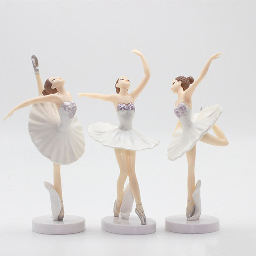 Three white ballerina figurines with purple accents on their tutus and shoes. The ballerinas are posed in different dance positions.
