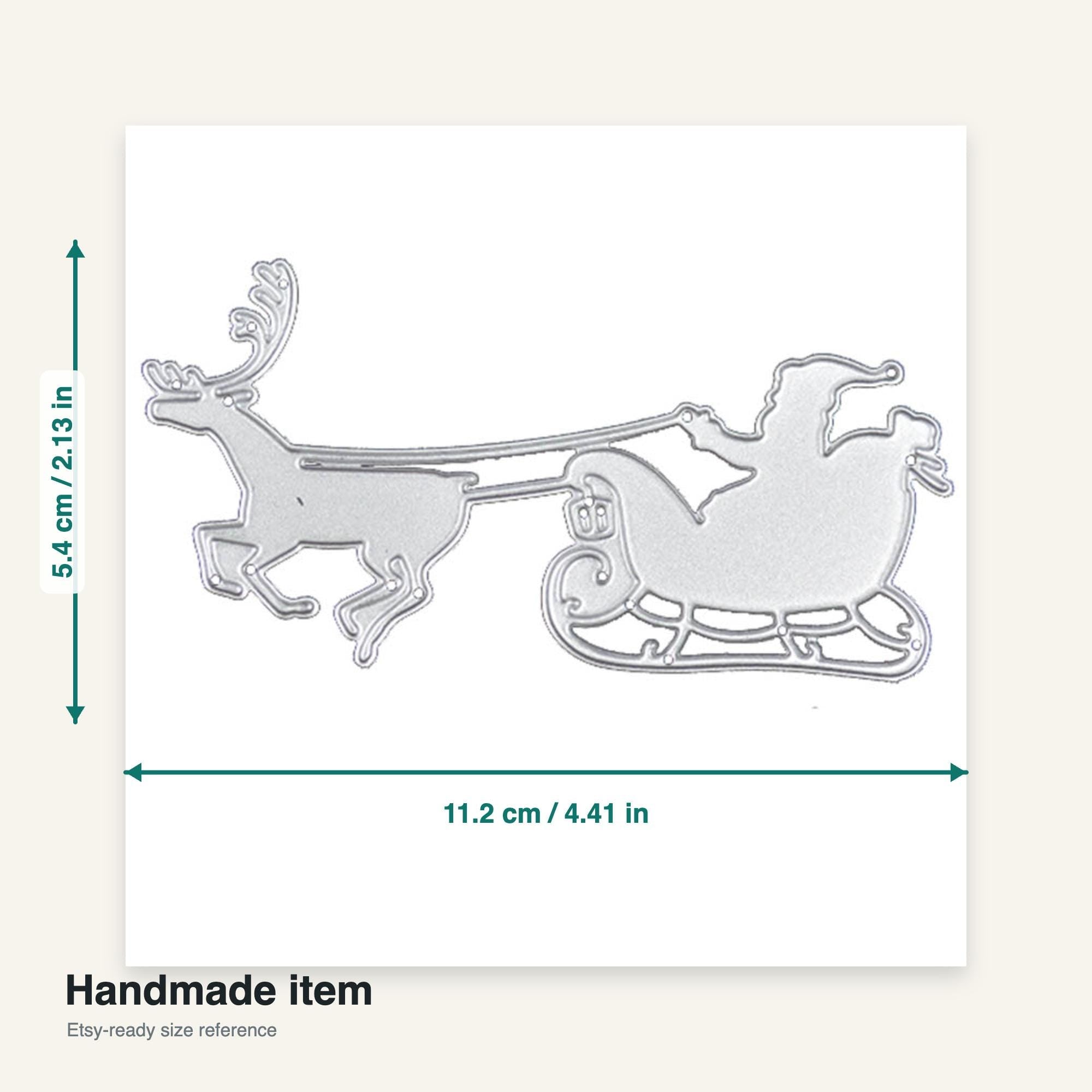 A silver-colored metal die-cut of Santa Claus in a sleigh being pulled by a reindeer. The die-cut measures 4.41 inches wide and 2.13 inches tall. The text "Handmade item" is at the bottom.