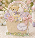 Pastel baby gift basket card with teddy bear, bunny, clothes, flowers, and bow