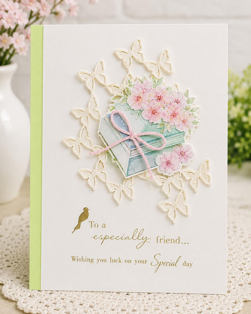 Friendship card with books, pink blossoms, pale butterfly border, and gold greeting